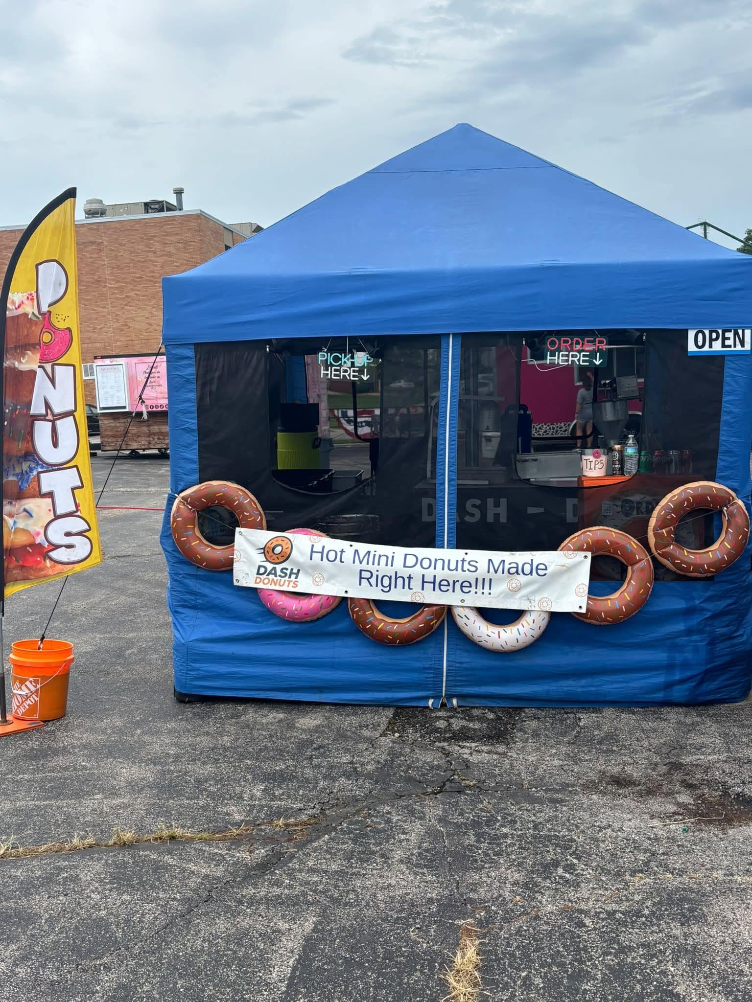 The Dash Donuts blue pop-up tent with a sign reading Hot Mini Donuts Made Right Here