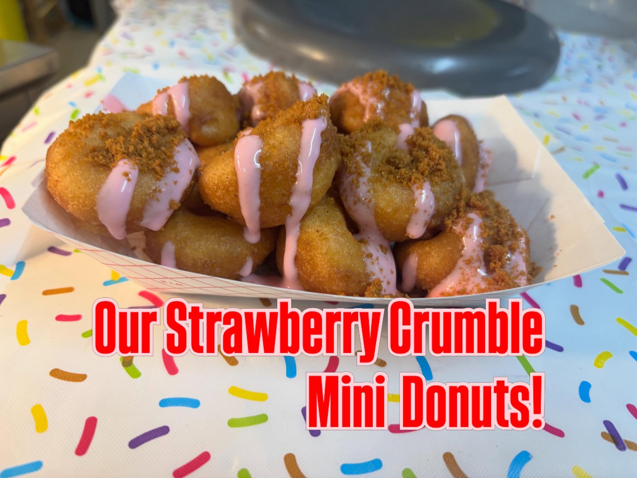 A paper boat of Strawberry Crumble mini donuts with pink icing and crumble topping